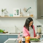 A woman blends fresh ingredients for a healthy smoothie in a stylish kitchen, promoting wellness.